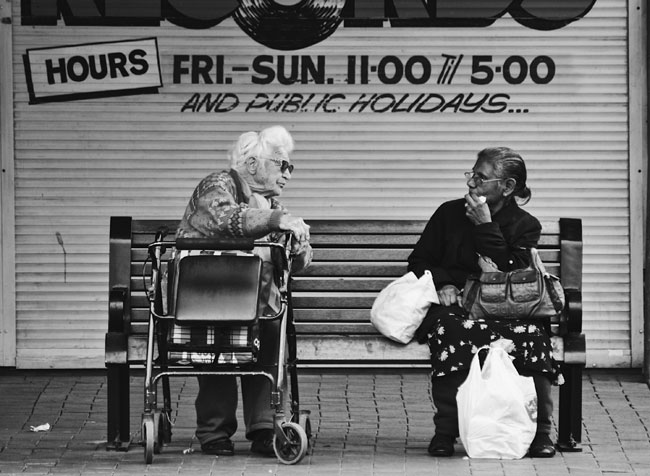 Dos mujeres charlando sentadas en un banco en la calle